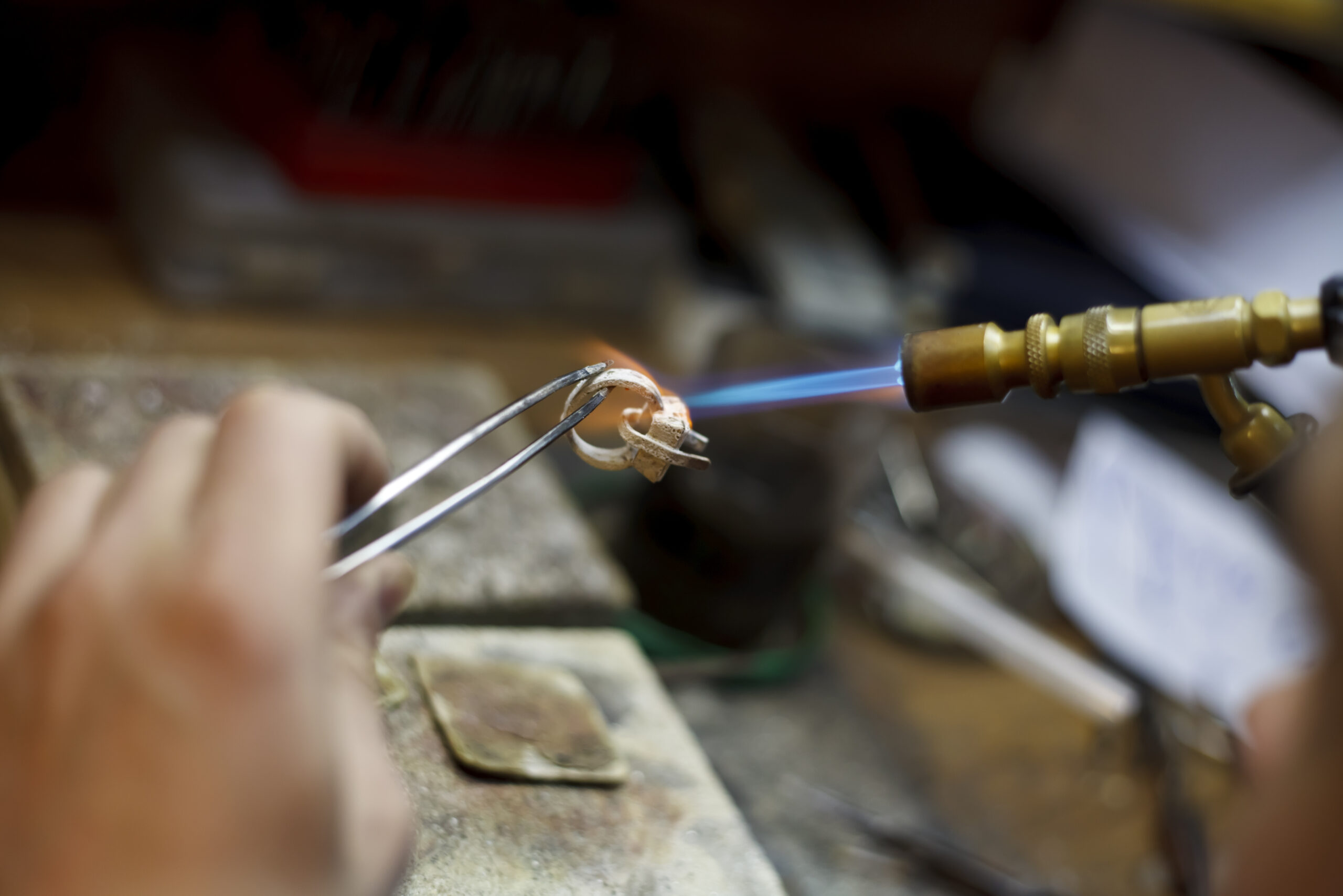 A jeweler uses a small torch to shape and adjust gold link jewelry