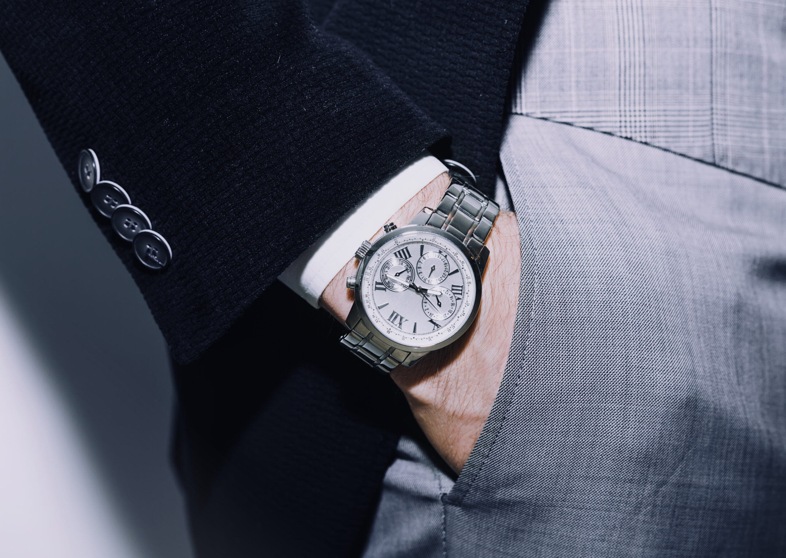 A man sticks his hand into his pocket as an expensive watch shows on his wrist