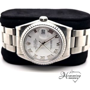 Rolex Datejust 36 with white dial and engine-turned bezel on a cushion.