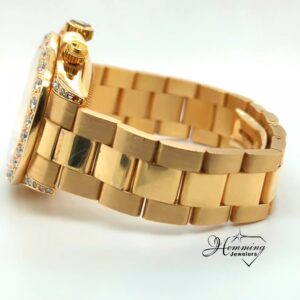 Side profile of an 18K gold Festina chronograph watch showing the diamond accents and gold bracelet.
